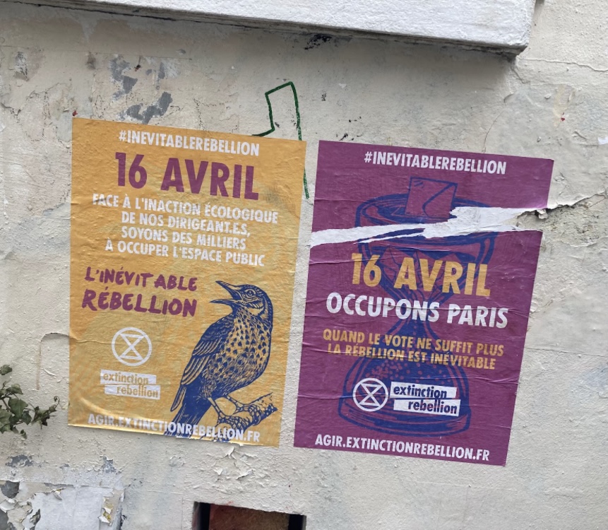 Two purple and yellow posters beside each other with French writing on them, one has a sketch of a bird cawing and the other has a sketch of an hourglass with an envelope bring stuffed into it